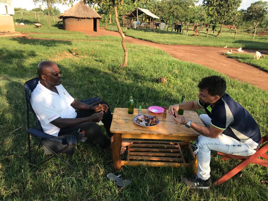 Thomas and friend sharing a meal in a Ugandan village